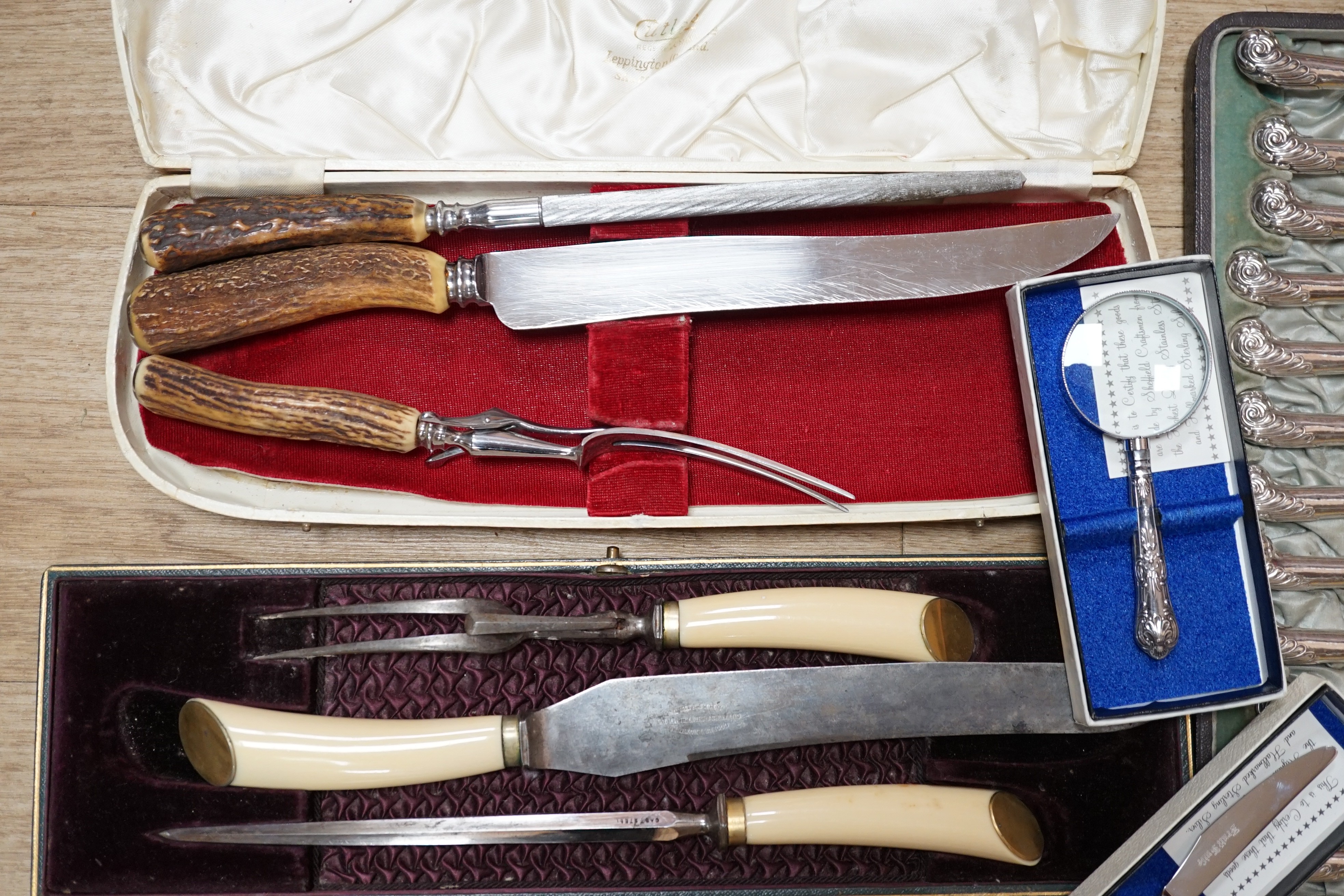 Two cased plated carving sets, a cased set of silver handled cake knives, a modern silver handled magnifying glass and cake slice.